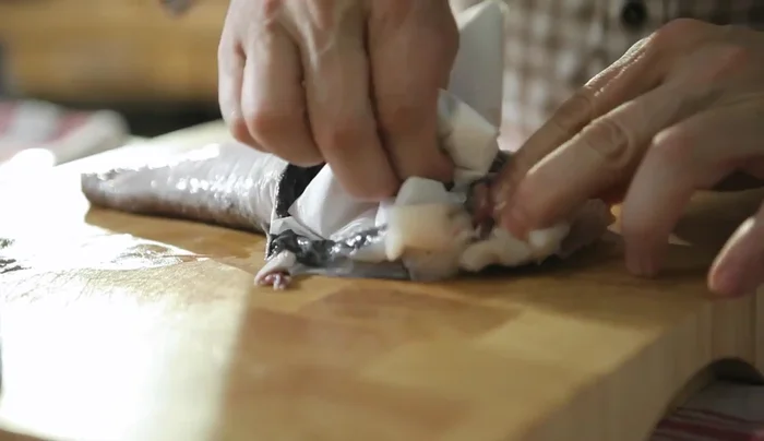 Tagliare le alette dei quattro filetti di pesce. Con l'aiuto di un foglio di carta assorbente, tirare via la pelle nera e la pellicola sottostante.