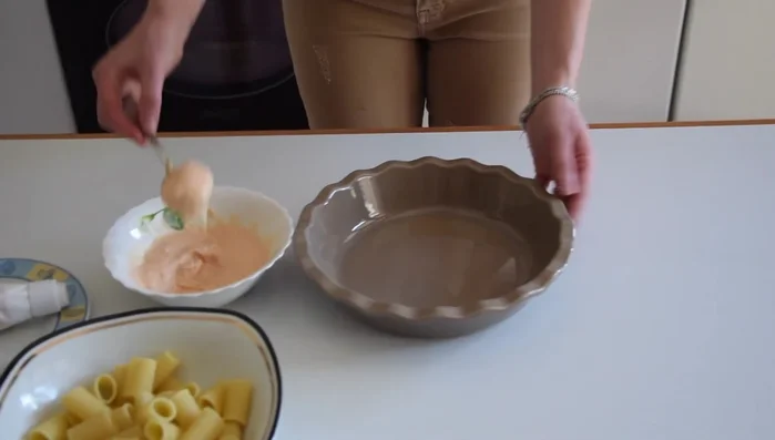 Mettere un po' di besciamella sul fondo di una teglia, disporre le mezze maniche ripiene, aggiungere altra besciamella sopra.