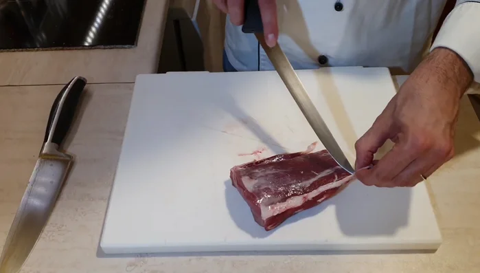 Eliminare il grasso in eccesso dal filetto di maiale con un coltello affilato.