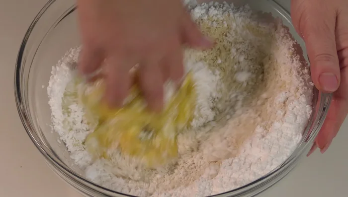 Mescolare con le mani tutti gli ingredienti. Se l'impasto è troppo duro, aggiungere altro albume; se troppo morbido, aggiungere altra farina di mandorle. Opzionale: aggiungere la scorza grattugiata di mezzo limone.