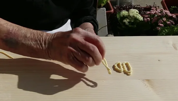 Rimuovere la pasta dalle dita e arrotolarla creando un cerchio attorcigliato, come caricare un orologio.