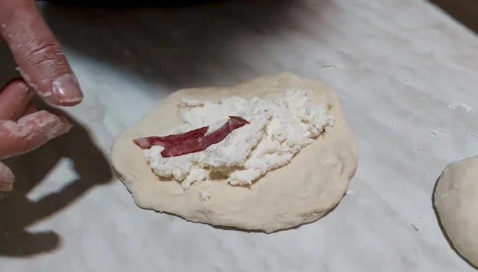 Aggiungere il ripieno di ricotta, salame e formaggio sulla base di ogni pizza.