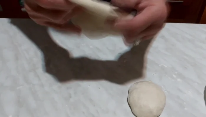 Stendere ogni parte dell'impasto con le dita, creando delle basi per le pizze.