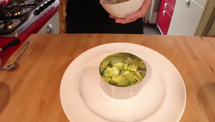 Prima versione della tartare: disporre l'avocado e il finocchio sul piatto, aggiungere il salmone, schiacciarlo leggermente con un cucchiaio e guarnire con sesamo. (260.91)