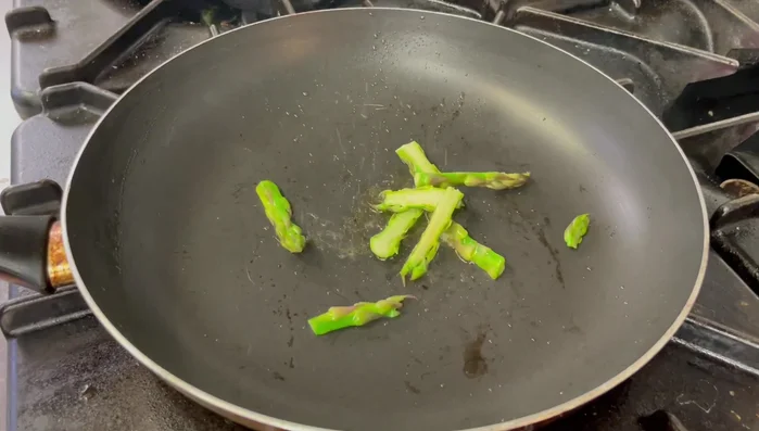 In una padella antiaderente, scaldare l'olio extravergine d'oliva. Rosolare le punte degli asparagi con un pizzico di sale fino a quando saranno croccanti (circa 1 minuto).