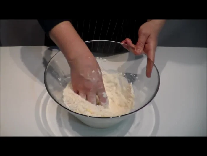 Aggiungere 250 g di farina setacciata e impastare a mano. Aggiungere 100 g di burro fuso e continuare a impastare fino ad ottenere un impasto omogeneo.