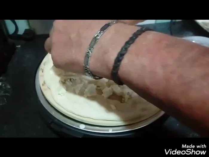 Condite la pizza con mozzarella, gorgonzola, noci e un filo d'olio d'oliva.