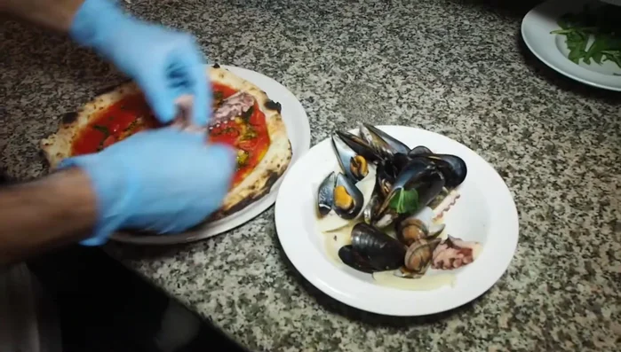 Aggiungere i frutti di mare (es. zampe di polpo, seppia) sulla pizza appena sfornata.