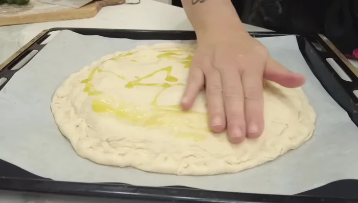 Fate un buchino al centro della pizza per far uscire l'aria e il vapore. Aggiungete origano e un filo d'olio (o un po' di farina) sopra.