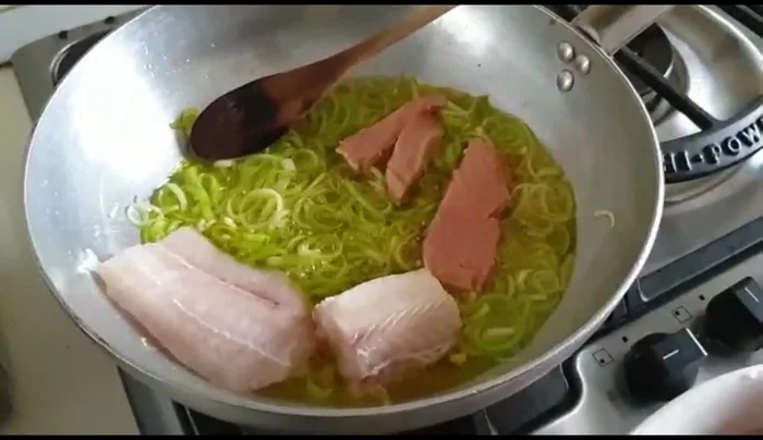Aggiungere il pesce (merluzzo, salmone, palombo) alla padella e cuocere per circa 3 minuti, mescolando delicatamente.