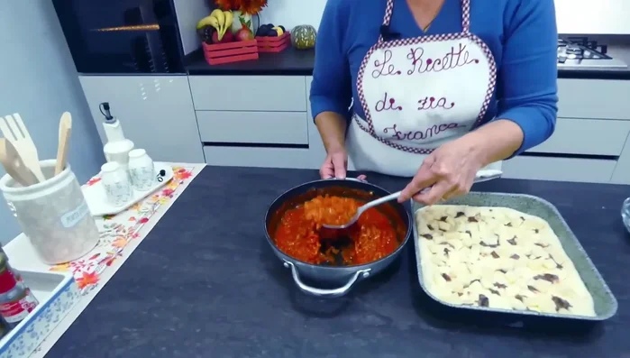 Distribuire il sugo di pomodoro sulle cipolle sulla pizza.