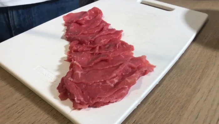 Affettare finemente il manzo creando il carpaccio e disporlo su un piatto, lasciando spazio al centro per gli asparagi.