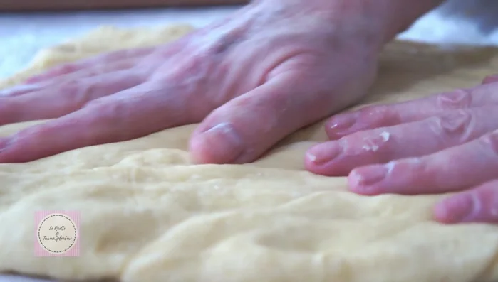 Rovesciare l'impasto lievitato sul piano di lavoro infarinato, schiacciarlo, piegarlo e stenderlo con il matterello a uno spessore di circa mezzo centimetro (193.68).