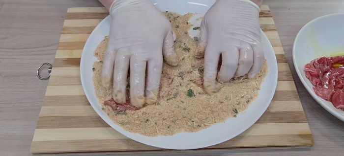 Impanare le fettine di carne nella panatura preparata.