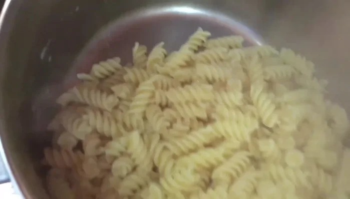 Scolare la pasta e aggiungerla al sugo di pomodoro. Mescolare delicatamente per amalgamare.