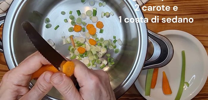 In un tegame largo, tagliare a pezzetti tre cipollotti (circa 60g), due carote e una costa di sedano. Soffriggere per qualche minuto con 5 cucchiai di olio d'oliva.