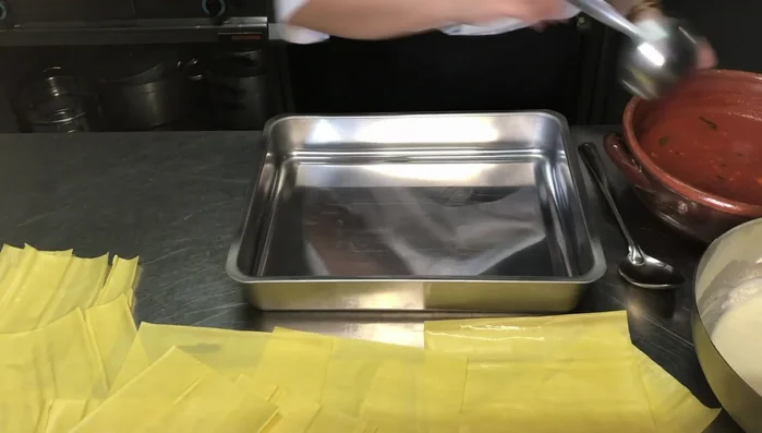 In una teglia capiente, iniziare a comporre la lasagna: stendere uno strato di pomodoro, poi uno strato di pasta, uno di besciamella e così via, alternando gli strati.