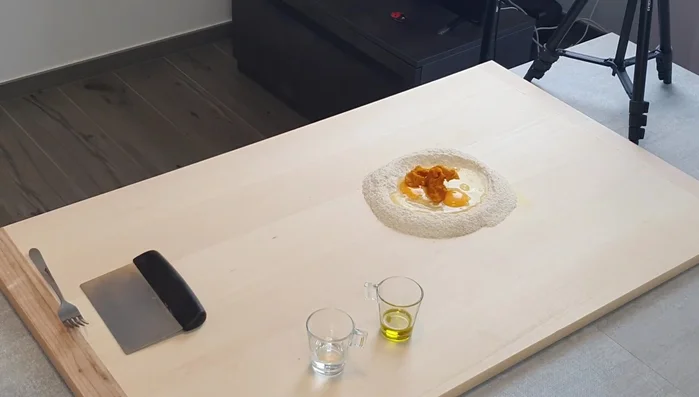 Preparare la pasta: mescolare semola, uova, zucca cotta al forno e olio extravergine d'oliva. Formare un panetto e farlo riposare.