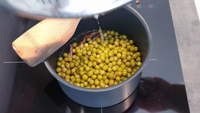 Aggiungere i piselli (sciacquati bene se sono in scatola) alla pancetta croccante. Se usate piselli freschi, pre lessateli brevemente.