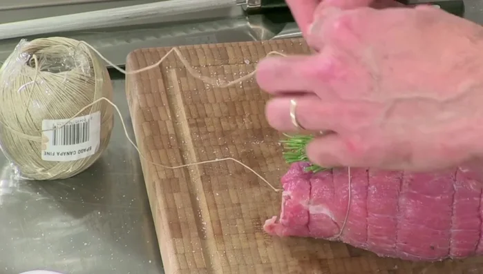 Legare l'arrosto con lo spago da cucina per mantenerne la forma durante la cottura.