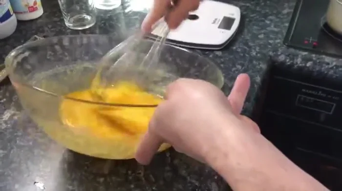 Aggiungere gradualmente il latte caldo al composto di uova e zucchero, mescolando continuamente.