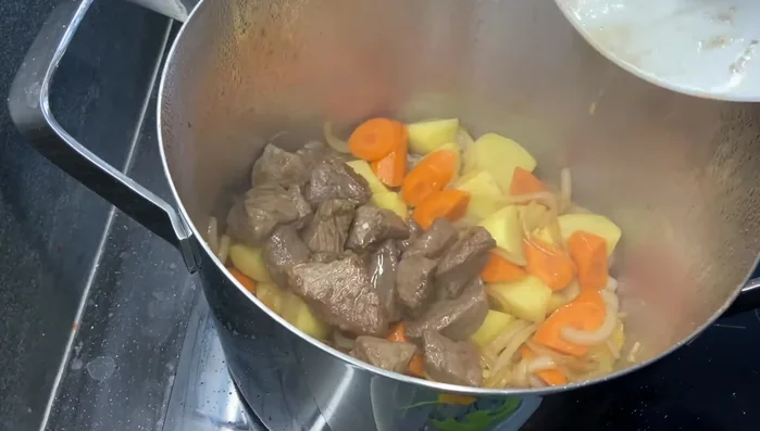 Aggiungere il manzo, 4 bicchieri d'acqua e mezzo bicchiere di vino rosso. Portare a ebollizione, rimuovere la schiuma e ridurre il fuoco a medio-basso.
