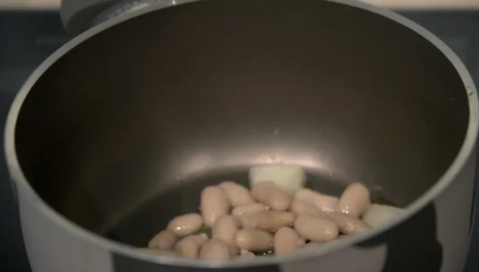 Aggiungere i fagioli cannellini, il guanciale tagliato a pezzi e i datterini pelati.