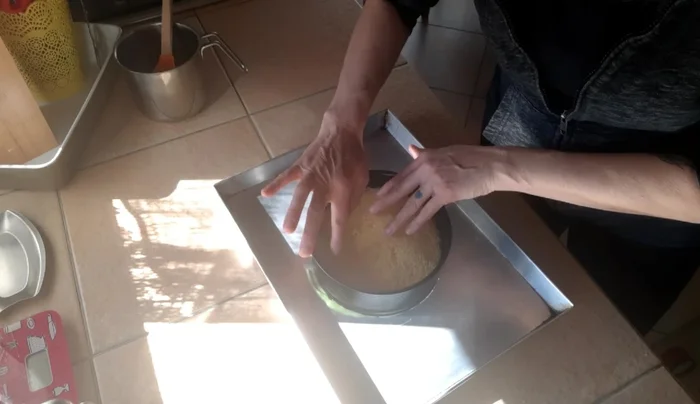 Nel frattempo, preparare il pan di Spagna (la ricetta non è inclusa nel video, ma si consiglia di utilizzare un pan di Spagna già pronto o di preparare uno in anticipo). Tagliare il pan di Spagna in modo da adattarlo alla dimensione della teglia e creare un disco rotondo.