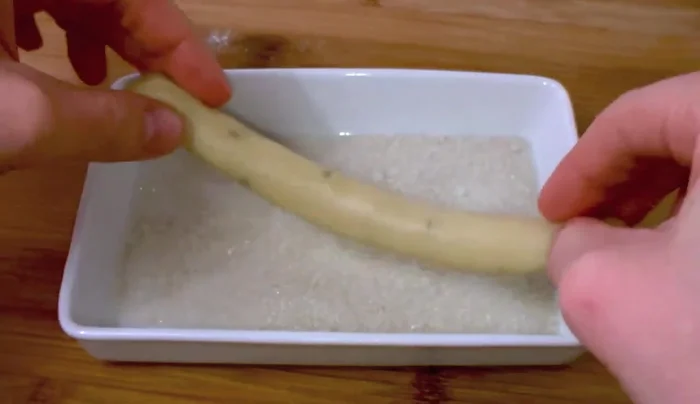 Passiamo ogni cordoncino in una ciotola con poco zucchero di canna. Chiudiamo le due estremità del cordoncino per formare una ciambella.