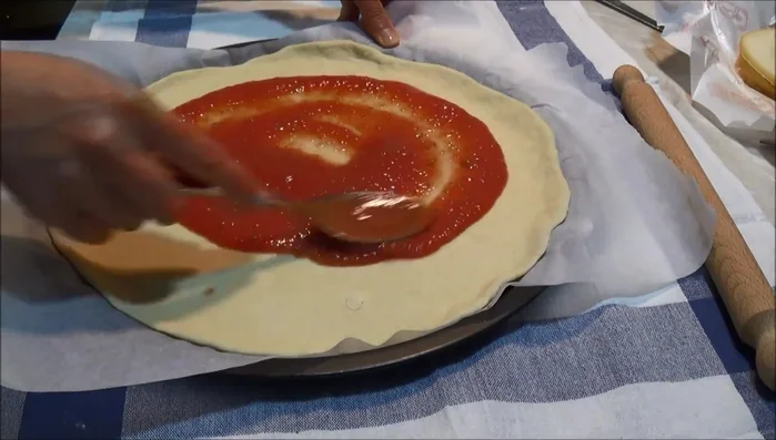 Spalmate la salsa di pomodoro sulla base della pizza.