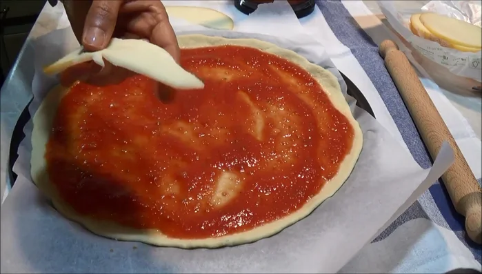 Aggiungete la scamorza affumicata a fette e il salmone affumicato sulla pizza, distribuendoli uniformemente.