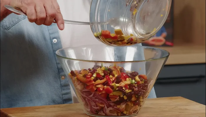 Aggiungere la salsa all'insalata, mescolare bene e condire con sale (se necessario).