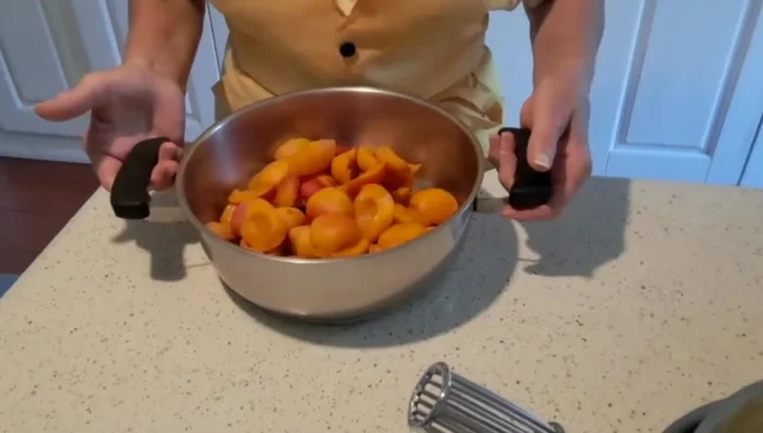 Preparare la frutta: pulire, lavare e tagliare le albicocche a pezzi.