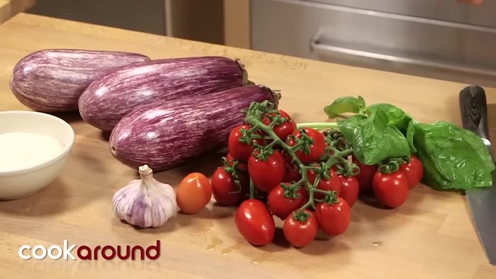 Preparare il ripieno: tagliare i pomodori a pezzetti piccoli (7.2). Aggiungere basilico spezzettato a mano e aglio tritato grossolanamente o spremuto (40.92). Condire con olio e sale (71.72). Lasciare riposare per insaporire (82.96).