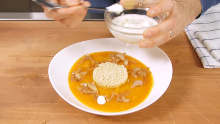 Disporre le cipolle caramellate sulla crema. Aggiungere yogurt, olio a crudo, e noce moscata.
