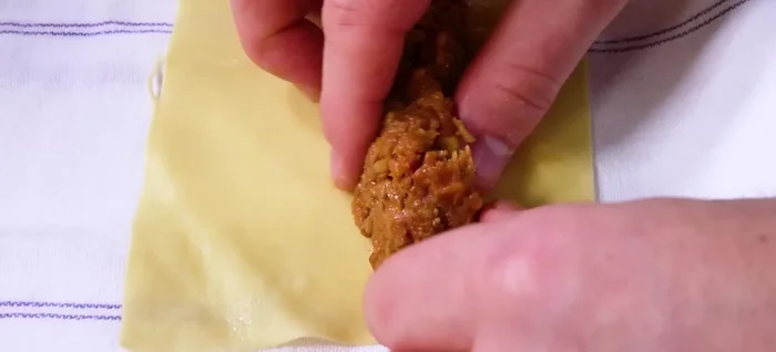 Farcire i rettangoli di pasta con il ragù, arrotolarli per formare i cannelloni.