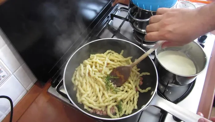 Aggiungere la pasta al guanciale nella padella. Regolare di pepe, aggiungere un rametto di timo e mescolare.