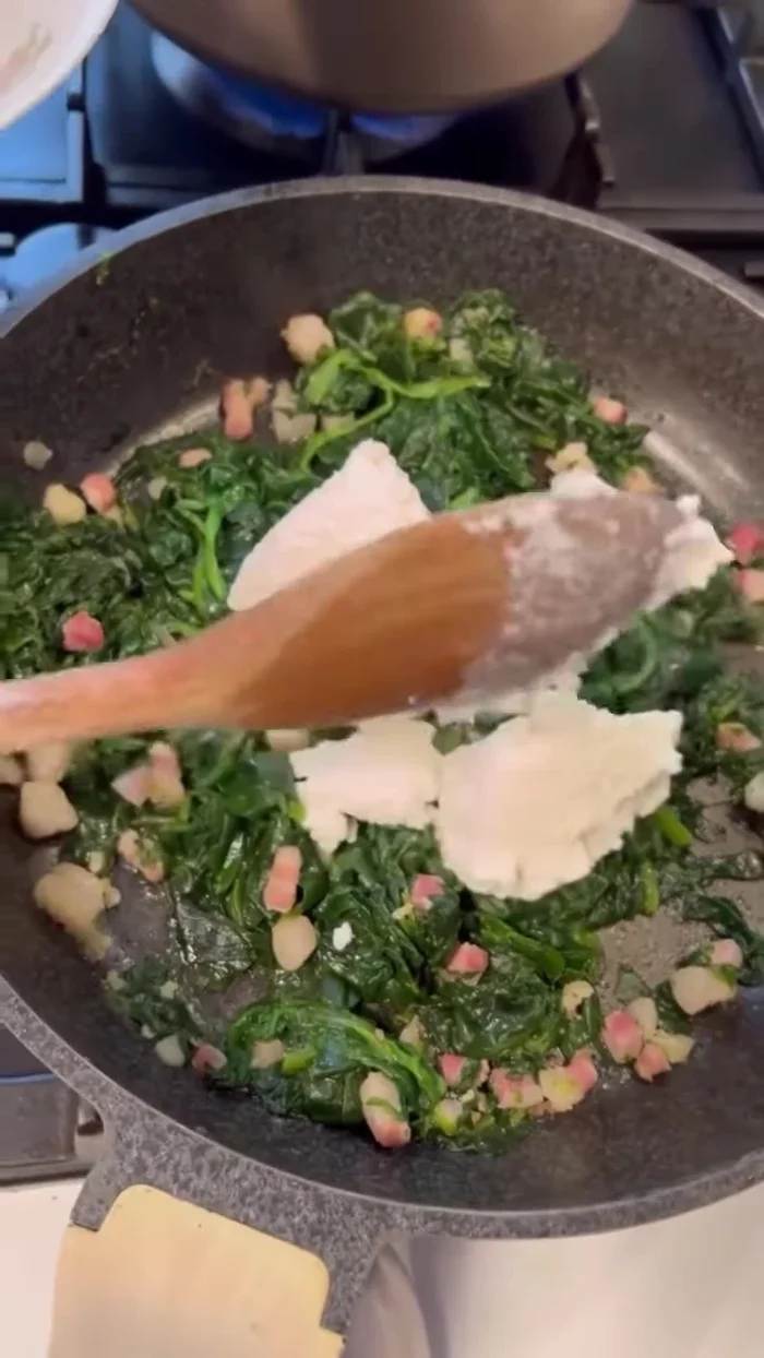 Aggiungere la ricotta di pecora al condimento di spinaci e guanciale. Mescolare bene, aggiungendo un mestolo di acqua di cottura per sciogliere la ricotta.
