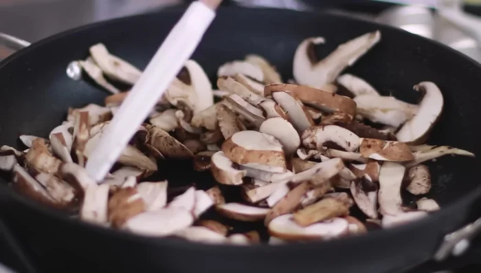 Nella stessa padella, cuocere i funghi affettati a fuoco medio-alto, fino a quando non rilasciano l'acqua e si dorano leggermente.