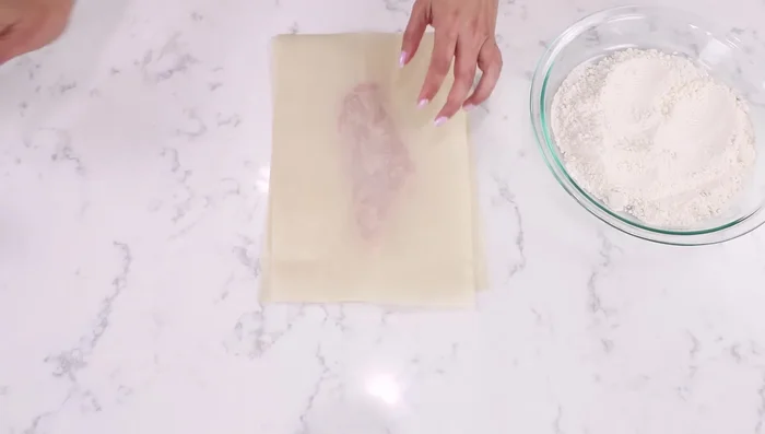 Appiattire i petti di pollo a uno spessore di circa mezzo centimetro, usando carta da forno o pellicola per proteggerli.