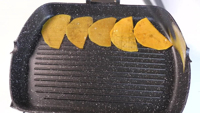Grigliare le fette di zucca in una padella a fiamma media per 3-4 minuti per lato.