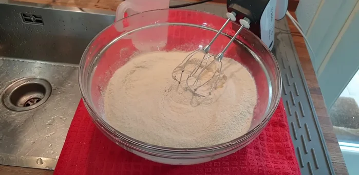 In una ciotola capiente, mescolate 1 kg di farina di grano duro con abbondante sale. Aggiungete gradualmente acqua (circa mezzo litro, ma dipende dalla farina e dall'umidità), mescolando fino ad ottenere un impasto liquido e omogeneo. (La consistenza deve essere tale da potersi stendere facilmente sul testo).
