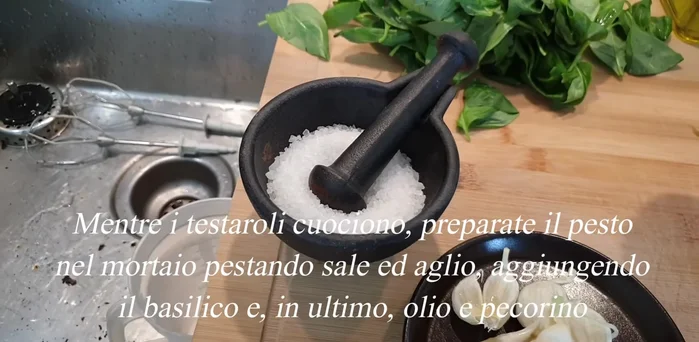 Nel mortaio, pestate l'aglio con un pizzico di sale grosso. Aggiungete il basilico e continuate a pestare, fino a formare una pasta. Incorporate l'olio extravergine a filo, amalgamando fino ad ottenere un pesto cremoso. (Se desiderate, aggiungete del pecorino).
