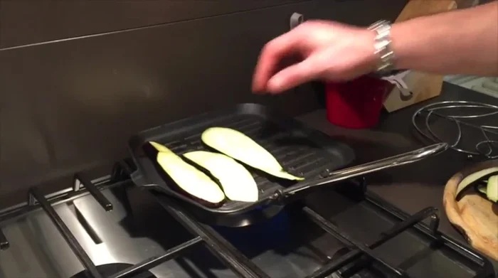 Cuocere le fette di melanzane sulla piastra calda, girandole per garantire una cottura uniforme. Lasciare cuocere finché non saranno leggermente abbrustolite.