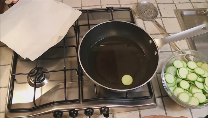 Verificare che l'olio di arachide sia caldo. Aggiungere le rondelle di zucchina alla padella.