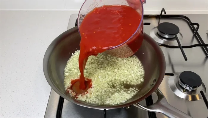 Aggiungere i pomodori schiacciati e il loro succo, mescolare bene.
