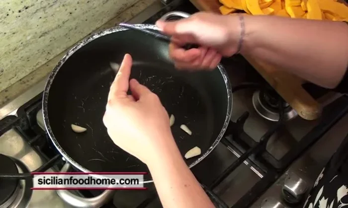 Aggiungere 2 spicchi d'aglio tagliati in quattro e farli dorare leggermente, poi rimuoverli dall'olio.