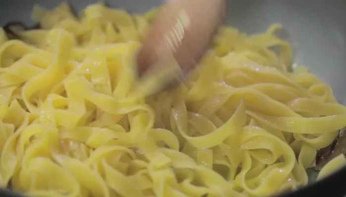 Mantecare la pasta nel sugo per amalgamare bene gli ingredienti.