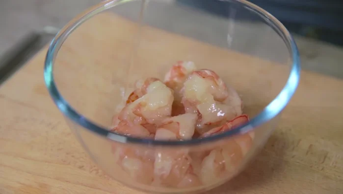 In un wok, scaldare l'olio di semi e rosolare i gamberi con curcuma per dare colore. Togliere i gamberi e tenere da parte.