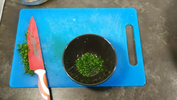 In una ciotolina, mettete metà del prezzemolo tritato, olio extravergine di oliva, pepe e sale. Mescolate per creare un olio aromatizzato.
